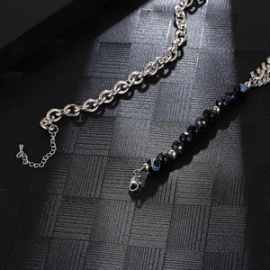 Detail of double-layer titanium steel chain and dark beaded bracelet on grid background