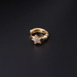 Macro shot of gold star-shaped hoop earring with sparkling zircon on black background