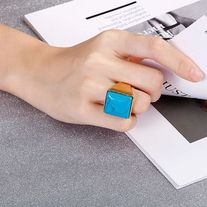 Anello quadrato alla moda con pietra azzurra su fascia placcata in oro indossato