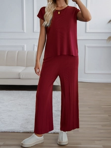Detailansicht eines roten ärmellosen Strickoberteils und einer weiten Hose im Set