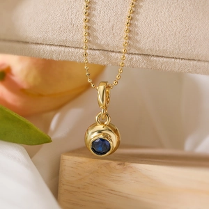 Gold ball pendant necklace with central blue zircon on a minimalist bead chain