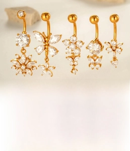 Macro detail of gold-plated navel rings featuring zircon butterfly and floral designs