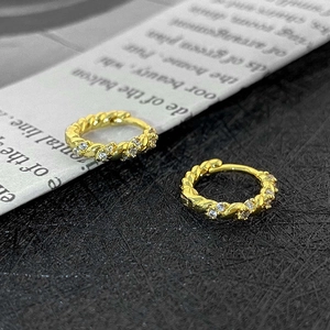 Macro view of gold twisted hoop earrings with sparkling white cubic zirconia stones
