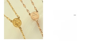 Macro detail of gold coin pendants featuring religious icons on a geometric titanium chain