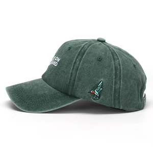 Detailed embroidery of a colorful hummingbird and text on a green washed cotton baseball cap
