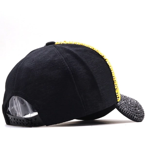 Detail view of the black baseball cap showing golden rhinestones and adjustable strap