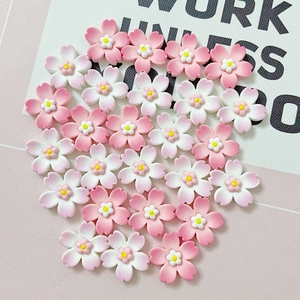 Pink gradient resin cherry blossom charms arranged in a heart shape for DIY crafts
