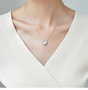 Detailed view of silver heart pendant necklace with pavé diamonds on elegant female model