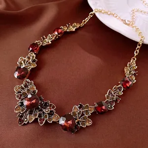 Vintage-style necklace with deep red crystals and antique gold leaf metal craftsmanship