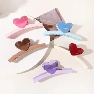 Macro view of five colorful heart-shaped hair claw clips with high-gloss finish