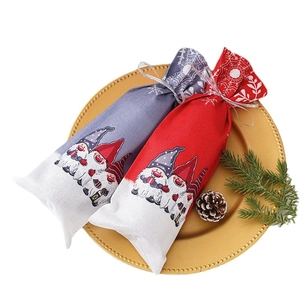 Christmas gnome wine bottle covers in red and grey colors on a gold tray with pine cones