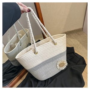 Detailed close-up of handmade woven straw tote bag with 3D daisy flower and rope handles