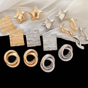 Detail showing assorted gold and silver knotted metal earrings on satin background