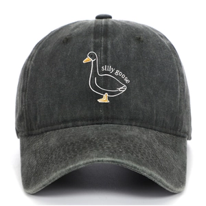 Detail view of cartoon silly goose embroidery on a washed dark gray cotton baseball cap