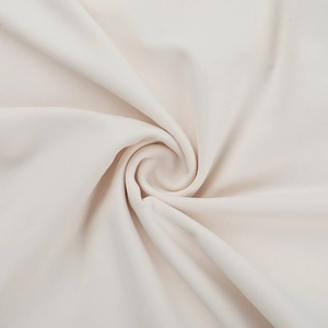 Détail de la texture du tissu en maille crème avec de doux motifs drapés en spirale