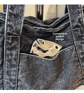 Detail view of the functional side pocket on the dark denim tote bag for easy storage