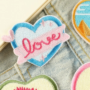 Toppa ricamata a cuore con ali e scritta Love su tessuto denim di colore chiaro