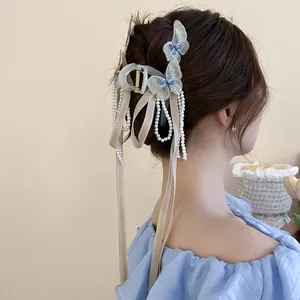 Dettaglio della pinza per capelli con ricamo a farfalla e nappine di perle bianche