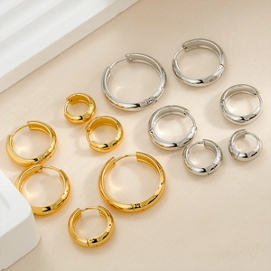 Polished gold and silver stainless steel hoop earrings in various sizes on a textured base
