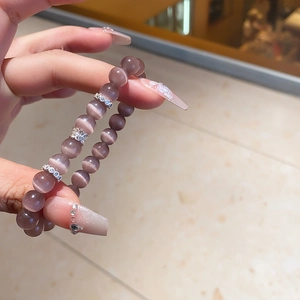 Detailed view of beaded bracelet with grey-purple cat eye stones and silver hollow charms