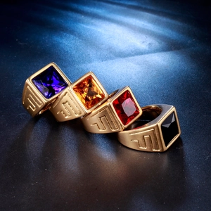 Close-up of four gold stainless steel rings with blue, orange, red, and black gemstones