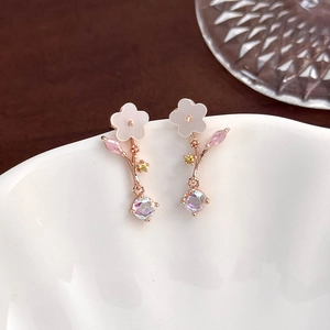 Macro shot of rose gold flower earrings with pink petals and colorful zircon drop pendant
