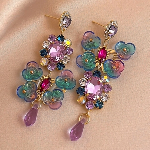 Close-up of colorful crystal flower earrings on champagne silk background