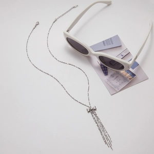 Détail du collier nœud Y2K en acier inoxydable avec pendentif franges et accessoires