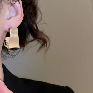 Close-up of minimalist silver geometric C-shape earrings on a model showing metallic luster