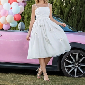 Detail of white midi dress featuring 3D floral appliqués and layered tulle fabric