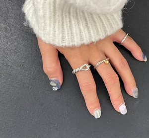 Close-up of three 925 silver knot rings and gold bead band worn on a hand