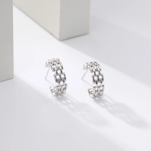 Detailed macro view of silver twisted woven geometric hoop earrings on white stone