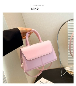 Close-up of pink structural handbag featuring glossy leather texture and gold hardware