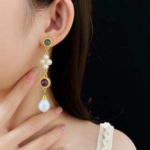 Detail of vintage gold tassel earring with pearls and gems worn by a model