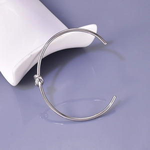 Detail of silver knotted open cuff bracelet made of polished stainless steel for women
