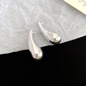 Macro view of polished silver water drop earrings featuring minimalist irregular geometry