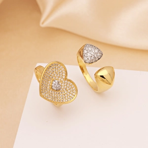 Golden heart-shaped rings with zircon pavé setting on soft silk fabric background