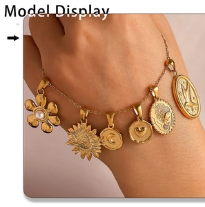 Detail of 18K gold plated charm bracelet with sunflower and pearl pendants on wrist