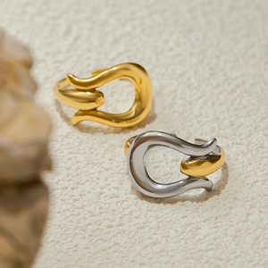 Minimalist gold and silver titanium steel U-shaped rings on a textured stone display