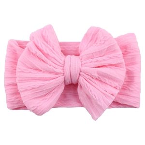 Detailed view of pink knitted baby headband featuring a large textured bow design