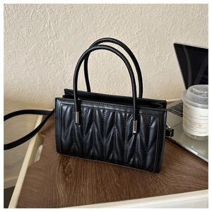 Close-up of black quilted leather handbag with silver metal hardware and top handle