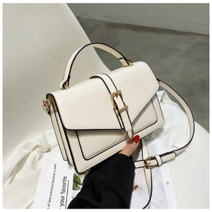 Detail view of cream white envelope bag with black edges and gold buckle closure