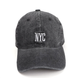 Detail of white NYC embroidery on vintage washed denim baseball cap with fabric texture