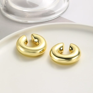 Detail of high-polished golden twisted ear cuff on white ceramic tray