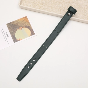 Macro detail of deep green leather wrist strap with metal buckle on white surface