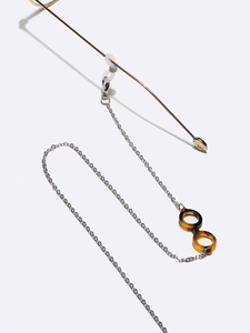 Detail of silver metal glasses chain featuring acetate leopard print charms on white background