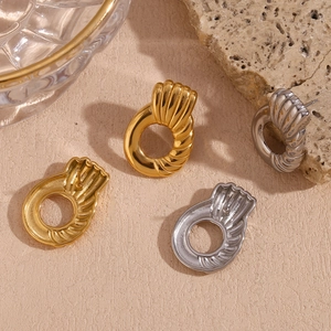 Detailed view of gold and silver textured geometric hoop earrings on a stone background