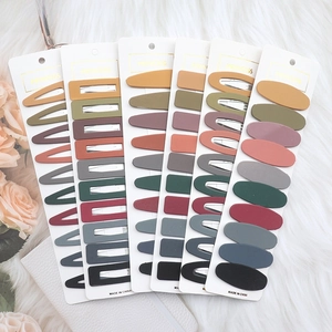 Flat lay of colorful geometric hair clips in various shapes on white plush background