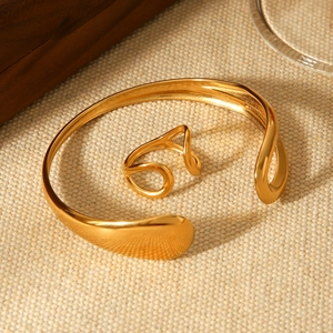 Minimalist gold teardrop open bangle and ring set on textured linen background