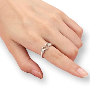 Detalle del diseño de manos formando un corazón en anillo abierto de plata en el dedo